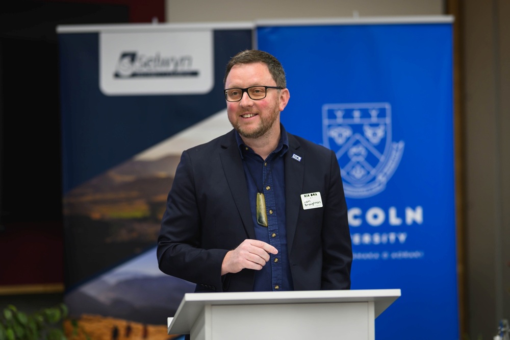 Mayor Sam Broughton smiling while speaking at a podium