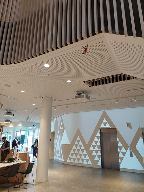 Elf toy swinging on railing with general public walking through library