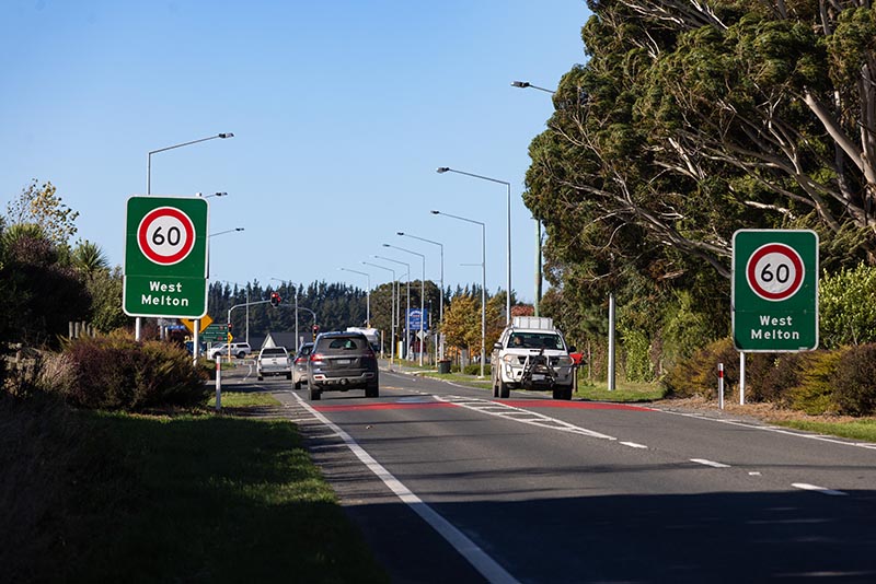 Cars drive by West Melton sign on the main road