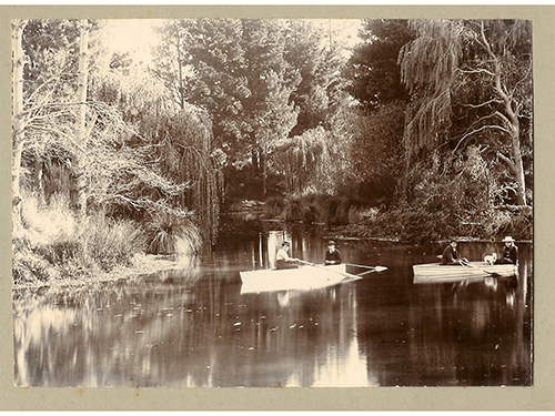 A historic photo in sepia of two people boating on a mill pond in Lincoln