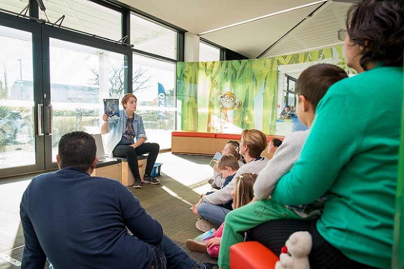 A group of families watch a reading in te reo at the library