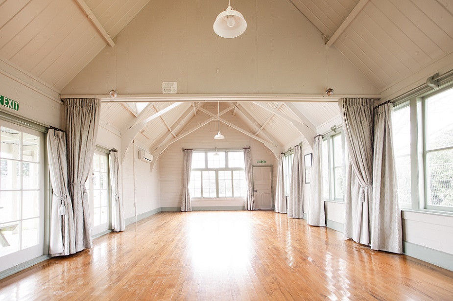 photograph inside the heritage Brookside Community Centre with a wooden floor and white walls and curtains
