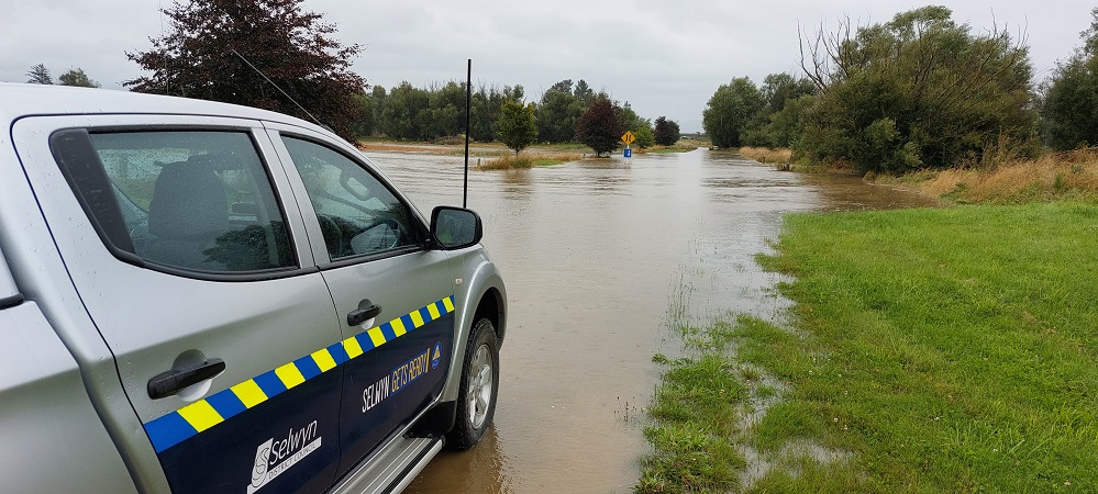 A Selwyn Civil Defence branded 4wd on the edge of a pool of flooding across a road