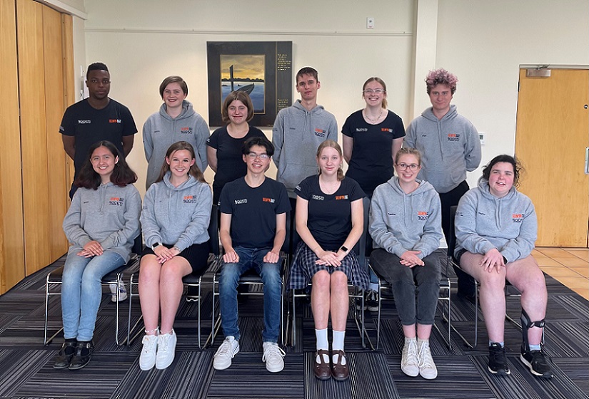 Formal youth council photo with members in two rows, front row seated, rear row standing, wearing monogrammed hoodies or t-shirts
