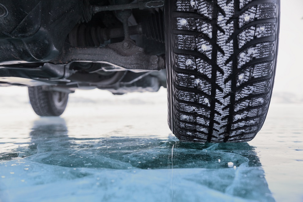 Close up picture of a car tire and the underside of a car on ice