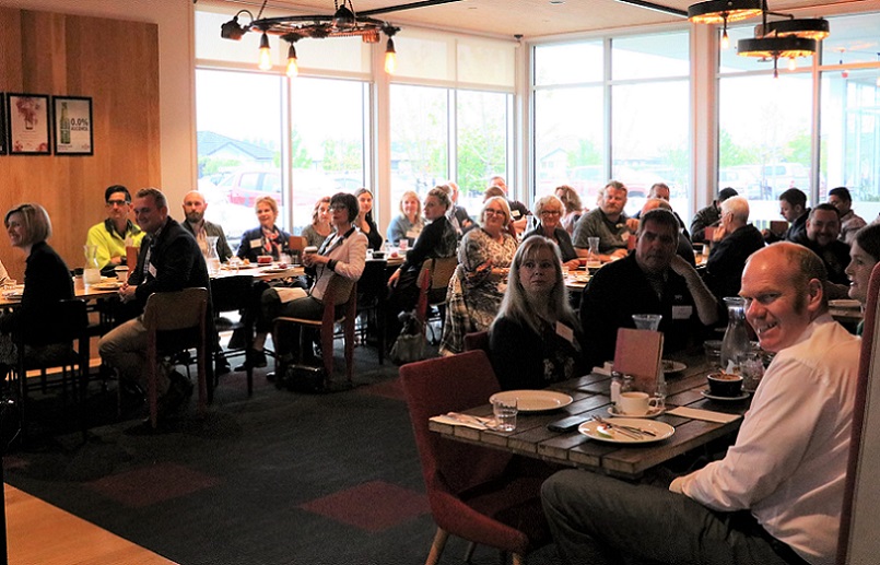 A crowd of people in a cafe turned listening to a speaker