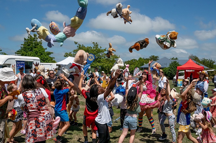 A crowd of children throwing teddy bears in the air