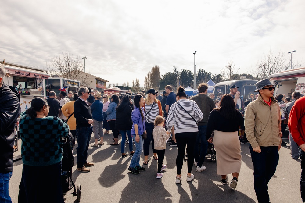A packed crowd moving between a line of food stalls and food vans at CultureFest