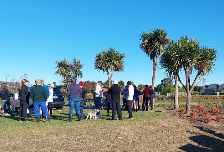 A crowd of people gathered next to a garden area in a reserve
