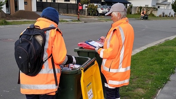 Two people checking recycling bin
