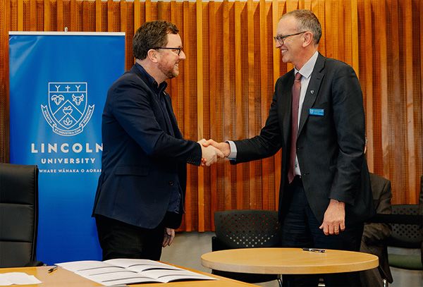 two men laughing and signing formal document