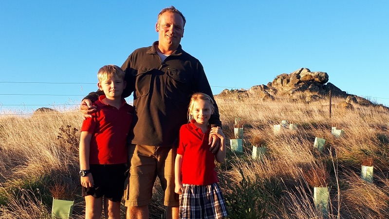 Farmer Andy Spanton and his children on a hillside with newly planted trees