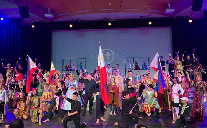 A crowd of people in traditional Filipino dress dancing with flags