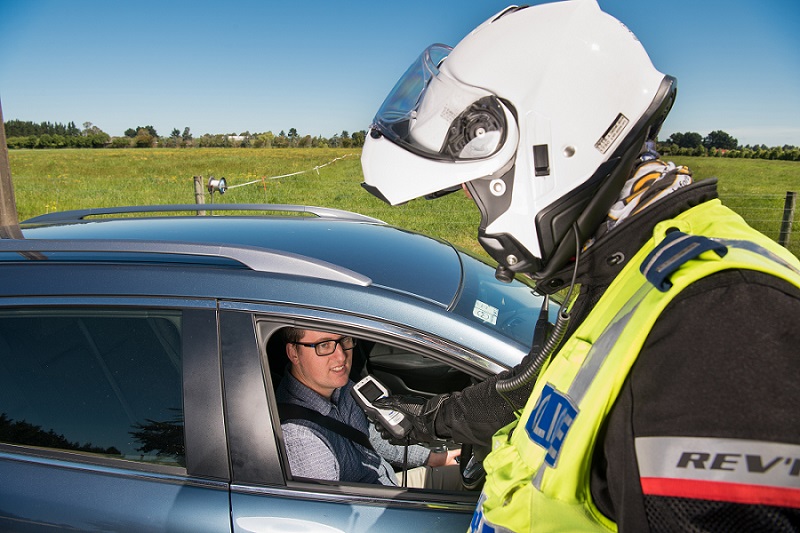 A man breathing into a breathelyser at a roadside police stop