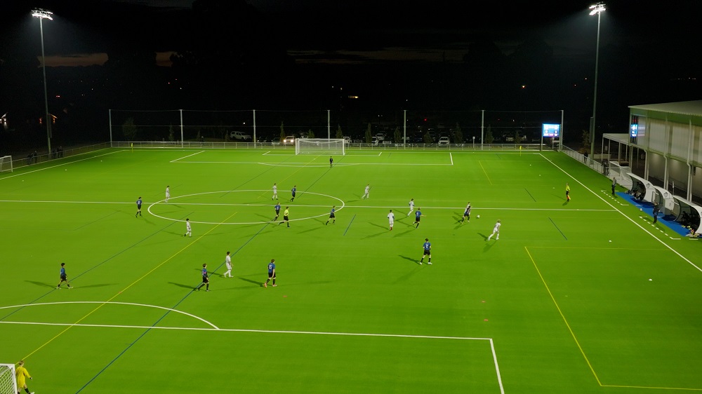 aerial image of a football game under lights in the dark on the artificial turfs
