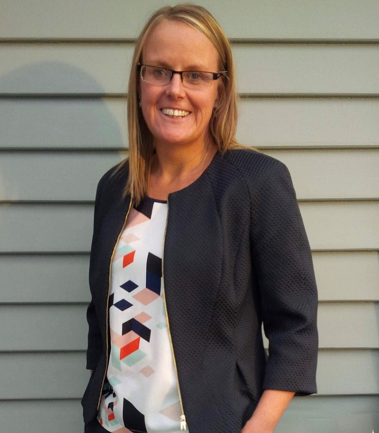 Woman with shoulder length straight blonde hair, glasses and black jacket
