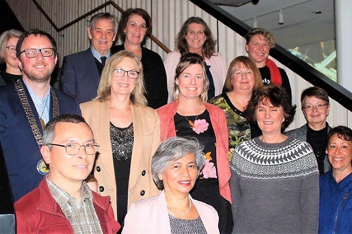 A smiling photo of the class and Mayor Sam on the main stairs at Te Ara Ātea