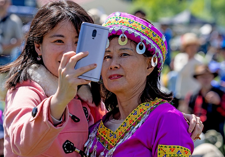 Two women, one in traditional Chinese dress, share a selfie