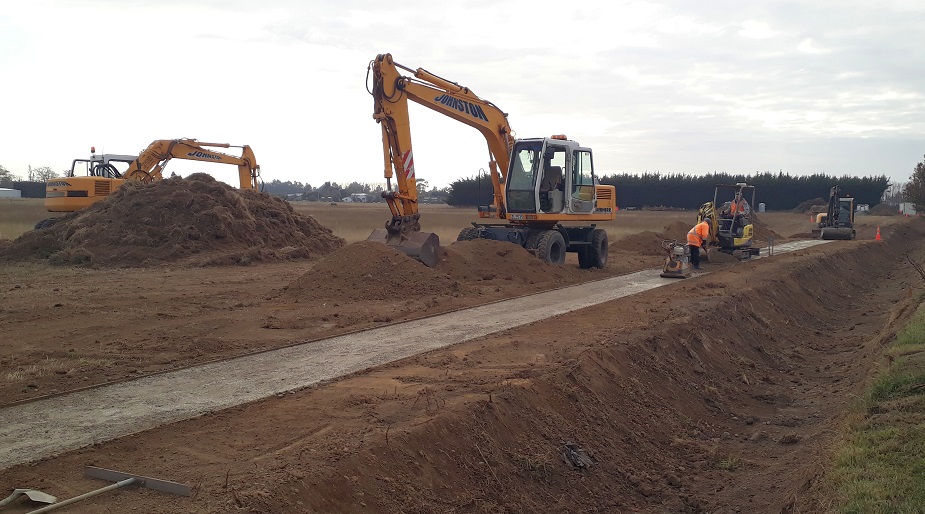Picture of a work site with bare earth, workers at work and two diggers