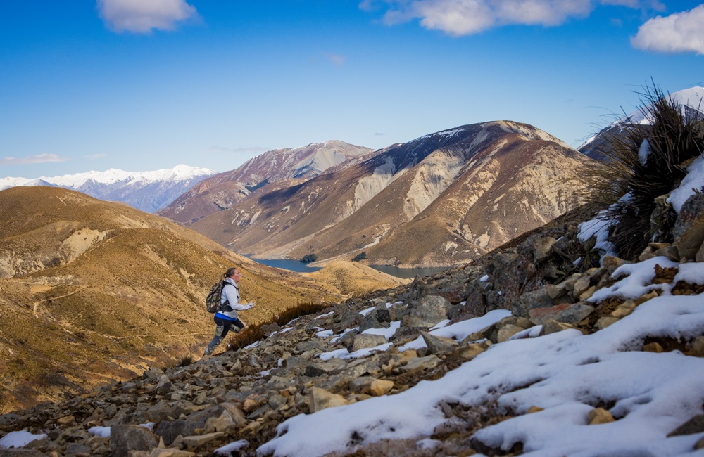 Woman running up a snowy mountain