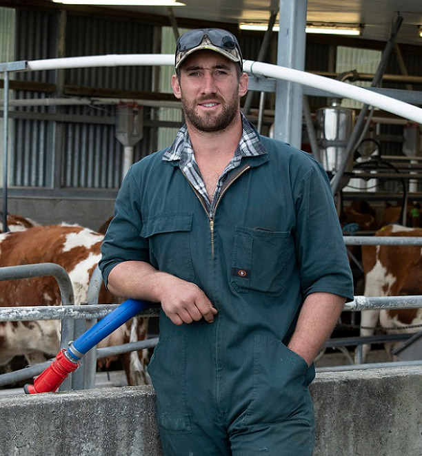 Farmer in boiler suit standing next to a milking shed