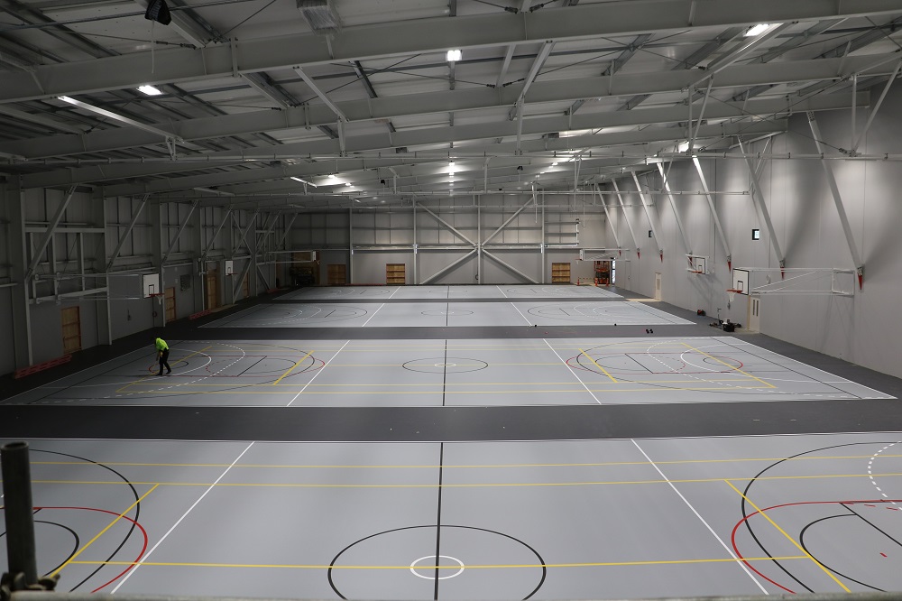 A view from above of the courts at the Selwyn Sports Centre with a man painting lines on a court