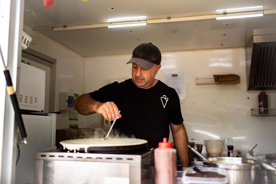 Man making crepe in food truck wearing black shirt with a crepe design on it