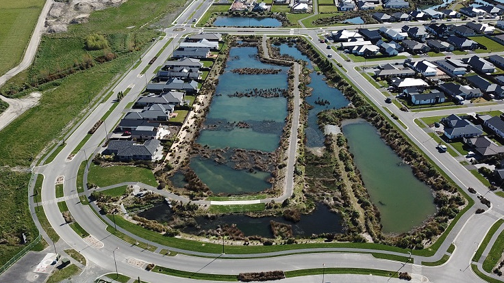 aerial image of a rectangular wetland pond surrounded by a road and houses