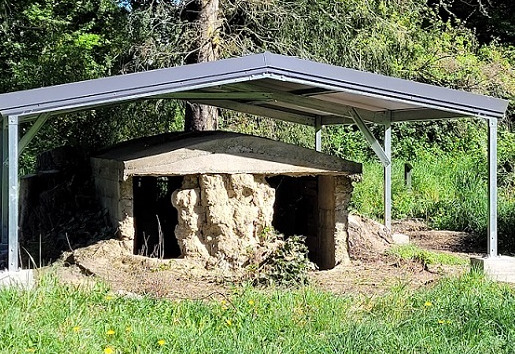 A low earth cottage covered by a metal roofed canopy