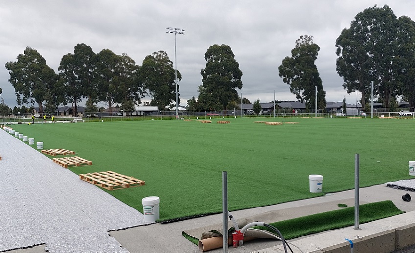 a field of astroturf with buckets and pallets placed around the outside at regular intervals