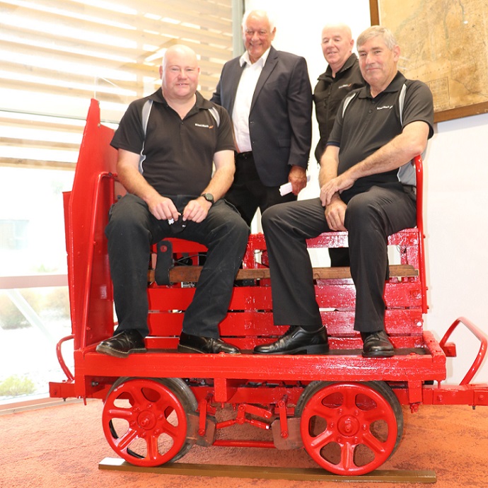 Four men sit on a red railway jigger