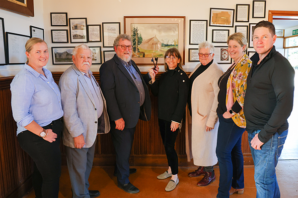 seven people in front of picture frame woman holding key