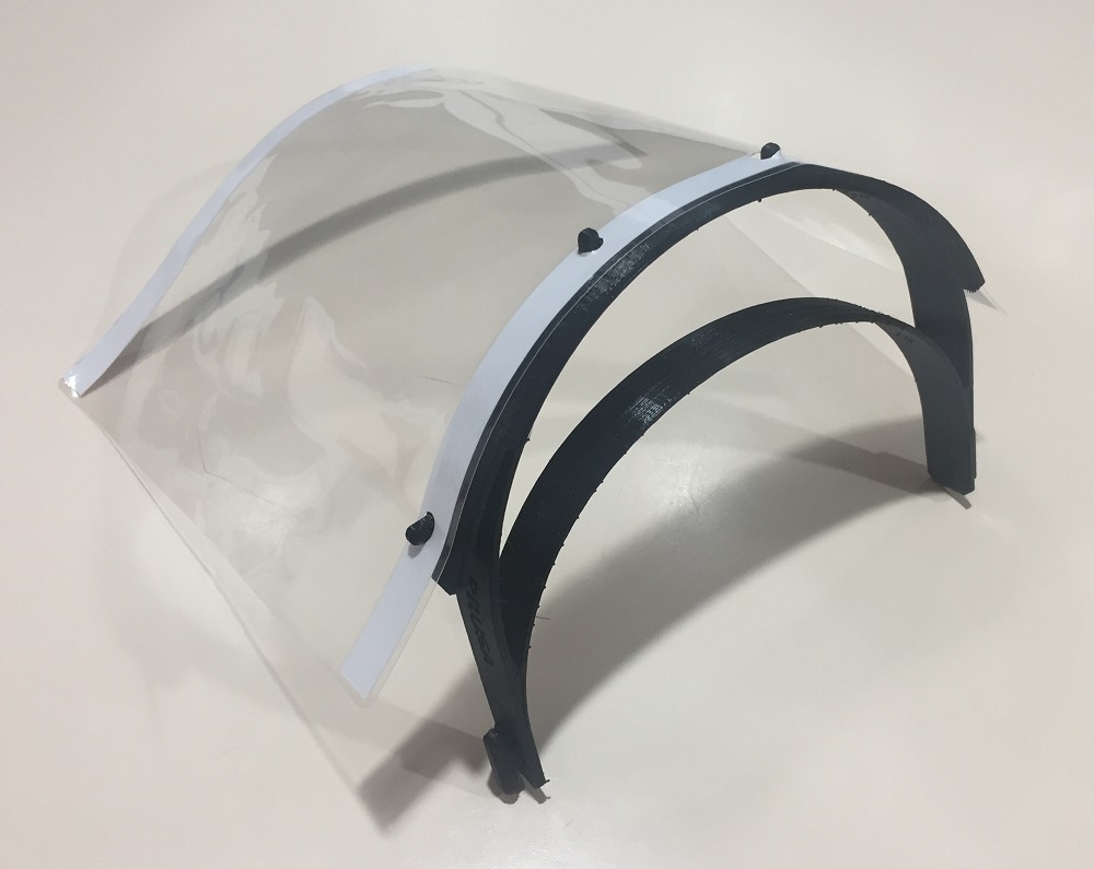A clear face mask with black clips on a white background 