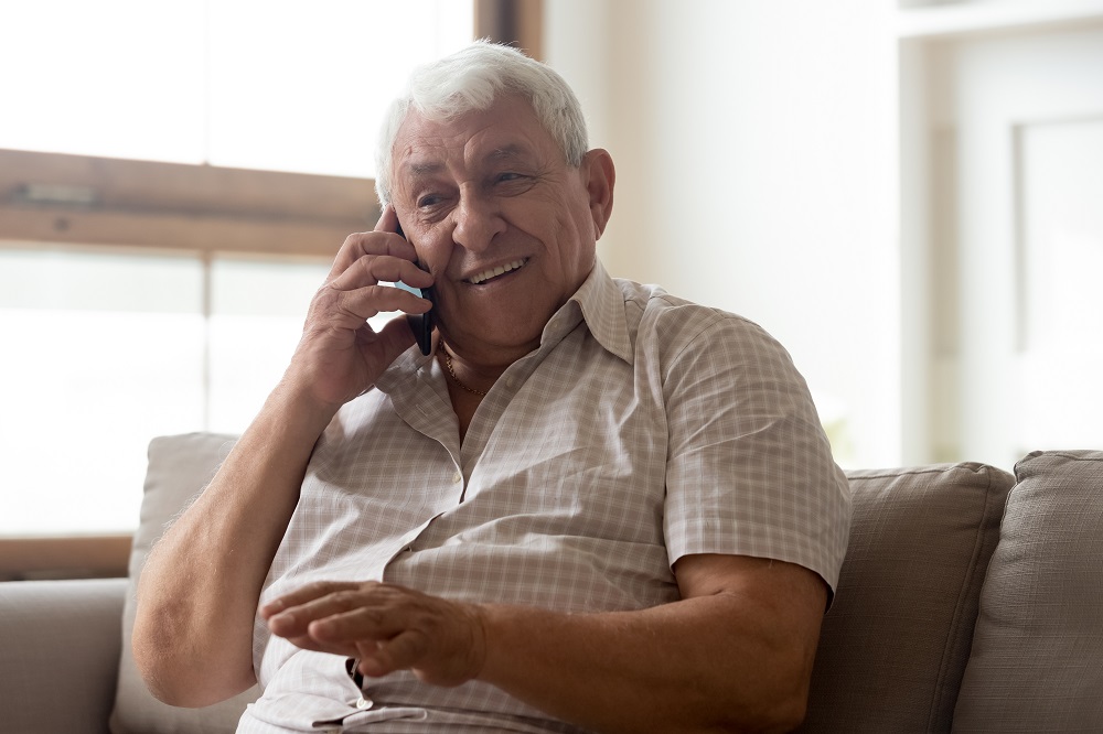 Older man talking on the phone sitting on a couch in a lounge