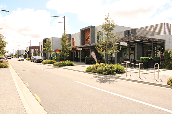View of a street with cars parked and driving down the street and business buildings on the right side