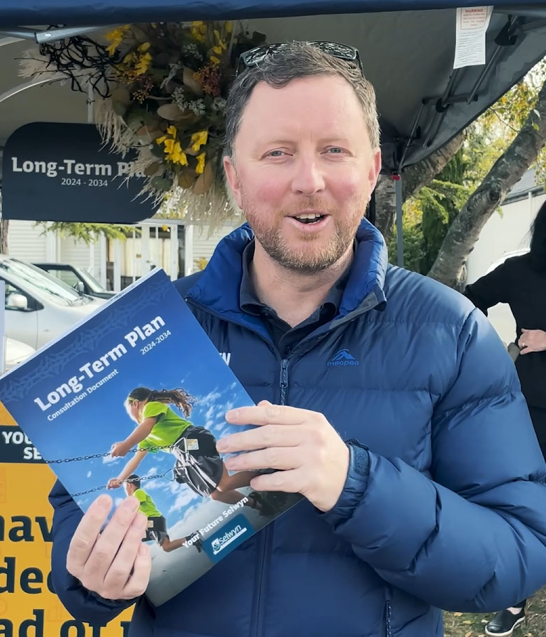 Mayor Sam holding a copy of the draft Long-Term Plan document