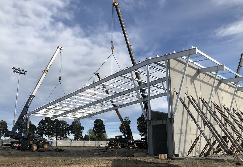 A crane lowers a roof frame in place at the Foster Park indoor courts worksite