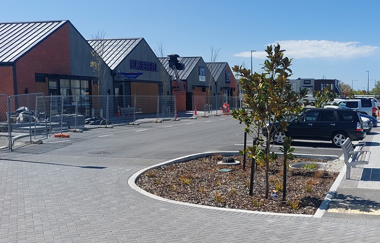 Three single story buildings bearing the logs of burgerfuel, lone star and majestic tea across a car park