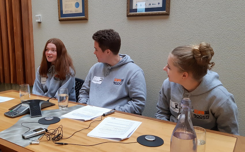 Youth Councillors Nevaeh Maeder, Laura Hann and Issy Kennedy sitting at desk with recording equipment recording an episode of the podcast
