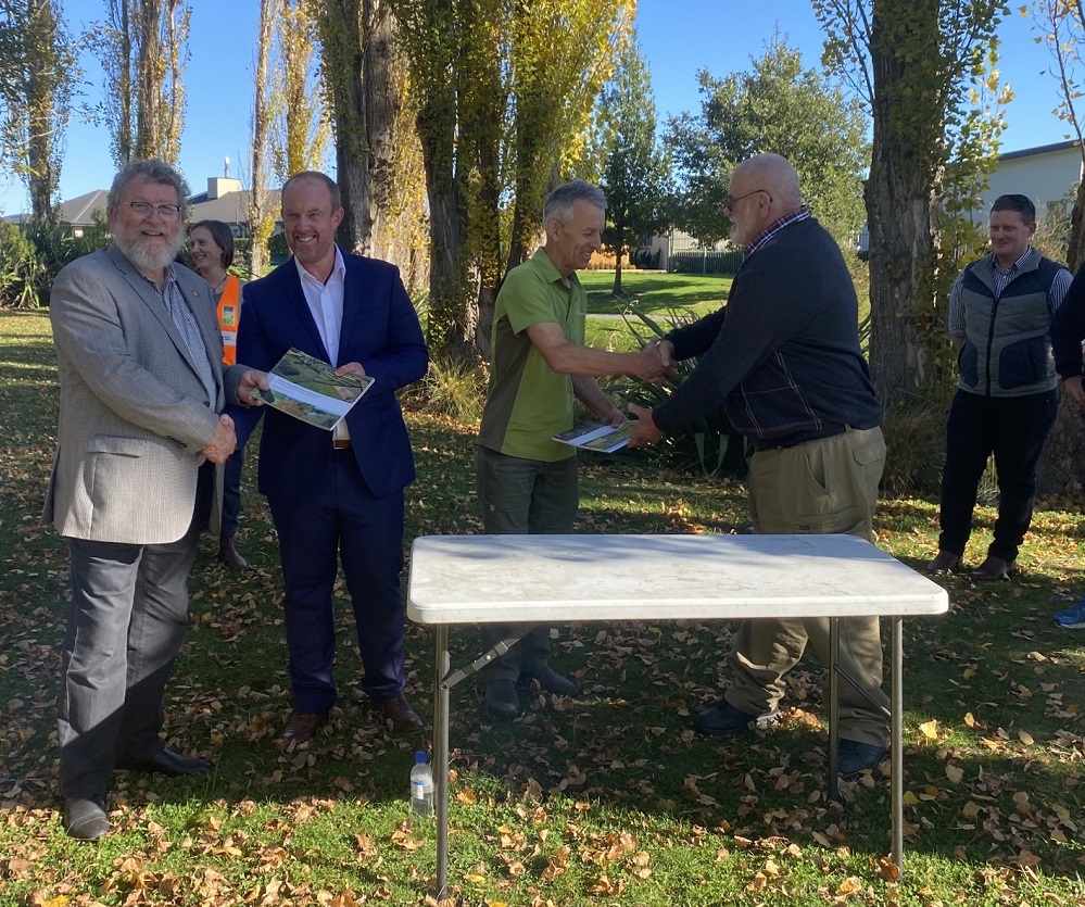 Representatives of the working group shaking hands and showing copies of the catchment management plan