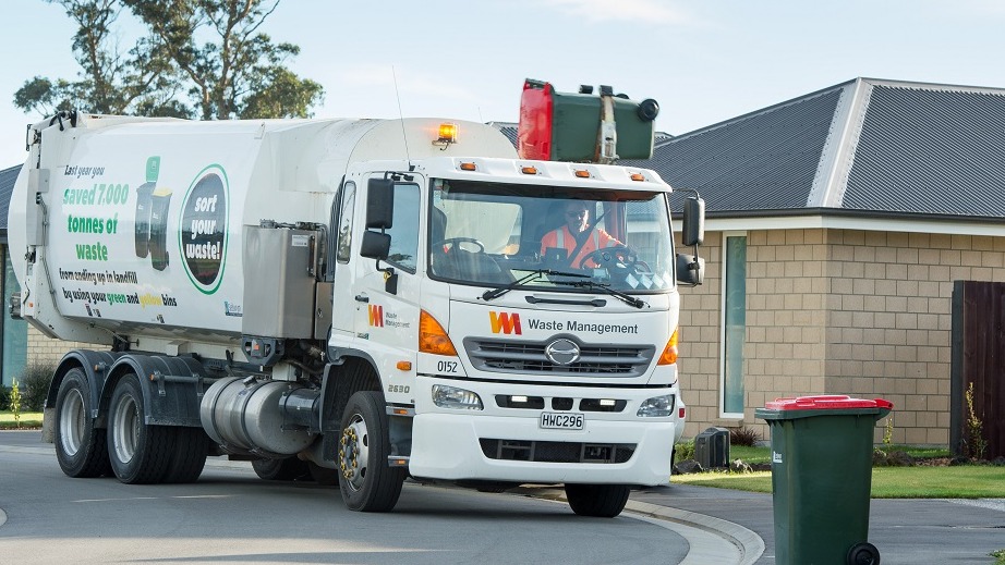 A rubbish truck collecting a red rubbish bin