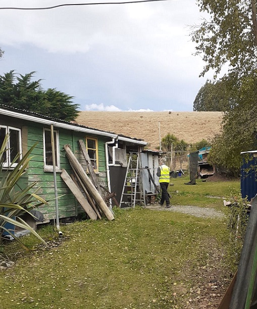 A man in yellow high vis jacket conducting a welfare check on a house