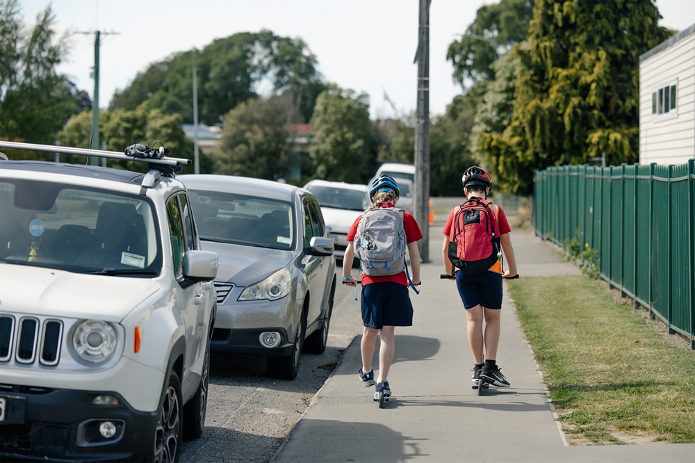 Children scootering outside a school