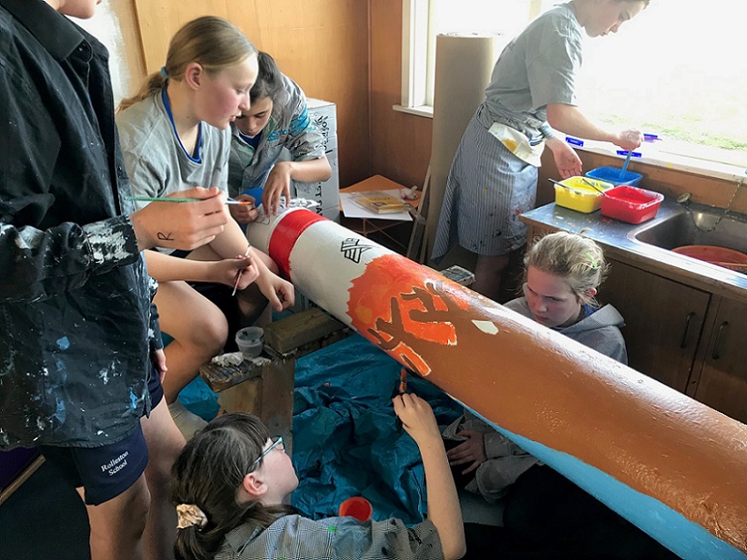 Children at Rolleston School in painting smocks painting a laid down pole