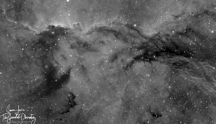 Black and white photo of stars and dust clouds in the shape of two dragons facing each other
