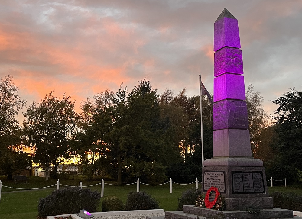 the Darfield war memorial at sunset lit up with purple lighting