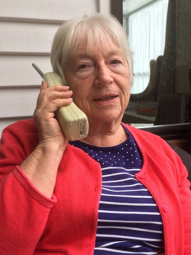 Older lady, short white hair and red jacket talking on a cordless phone