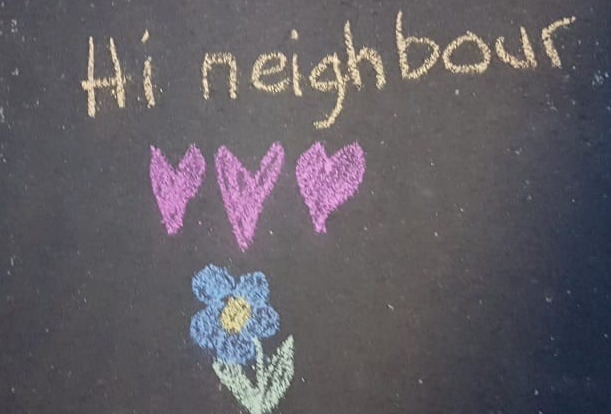 The words hi neighbour written in chalk on a pavement with a drawing three love hearts and a flower