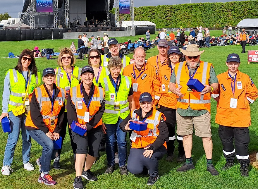 A group of people in high visibility yellow or orange jackets holding branded collection boxes