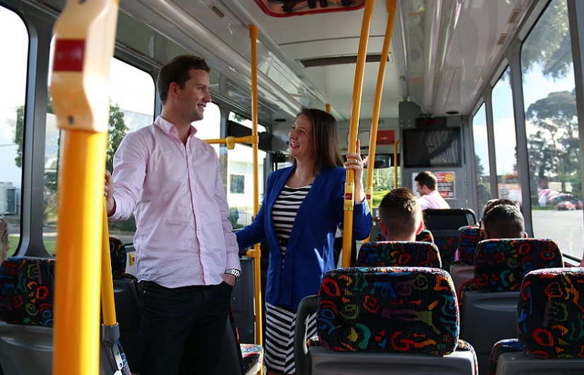 A man and a woman talk while standing on the bus